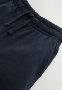 Marineblå joggingbukser lavet af blød bomuld, med elastisk taljebånd med snore og subtil tekstur. Foldet ved kanten.