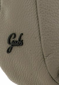 Superficie de cuero gris con un acabado texturizado y un logotipo negro que dice "Gabs" destacado de manera prominente.