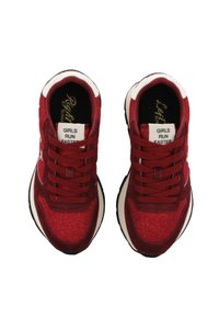 Sneaker rosse con una texture glitterata, caratterizzate da accenti bianchi, lacci spessi e un colletto imbottito. Le etichette recitano "LE RAGAZZE CORRONO PIÙ VELOCE."