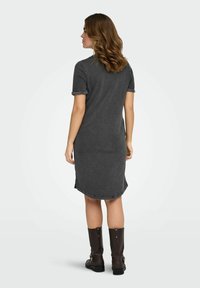 Hall, põlveni ulatuv kleit pehmest kangast, lühikeste üleskeritud varrukatega ja küljetekitustega. Sobitatud pruunide, vöödega põlveni ulatuvate saapadega.