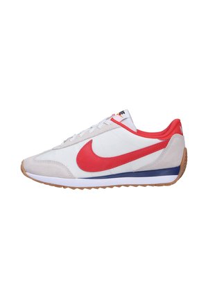 Witte sneaker met een rode Nike swoosh, suède accenten en een rubberen gumzool. Beschikt over een laag ontwerp en een bovenwerk van gestructureerde stof.