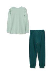 Lange mouwen lichtgroen shirt gecombineerd met donkergroene broek met elastische taille. Beide zijn gemaakt van zachte, ademende katoenen stof.