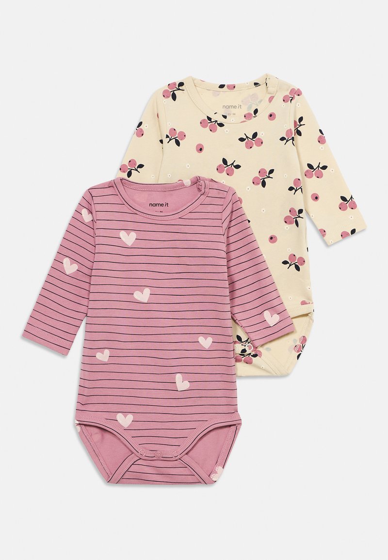 Deux bodies bébé à manches longues, l'un rose avec des rayures noires et des cœurs blancs, l'autre crème avec des imprimés cerises et fleurs roses.