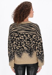 Beige �és fekete mintás pulóver állatmintákkal, puha textúrával, széles ujjakkal és flitterekkel díszített szegéllyel.
