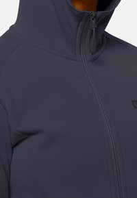 Mörkgrå zip-up jacka med hög krage, slät textur och en liten logotyp fram. Har en framträdande dragkedja och ett strömlinjeformat design.