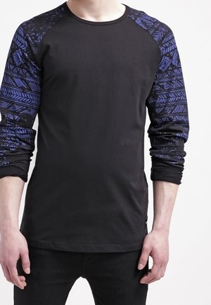 Koszulka z długim raglanowym rękawem z czarnym korpusem i niebieskimi rękawami w geometryczne wzory. Wykonana z miękkiego materiału o dopasowanym kroju.