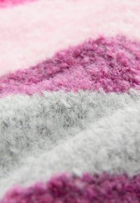 Stickad tyg i rosa, lila och grå diagonala ränder; mjuk textur med en luddig yta; olika tjocklek i varje färgsektion.