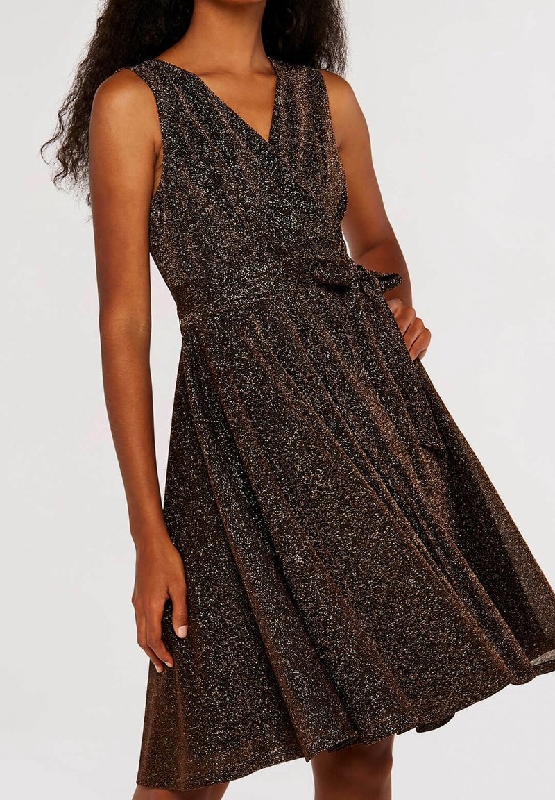 Bronze glitter dress with a V-neck, sleeveless design, and a fitted waist. Features pleated skirt and a tied bow detail at the waist.