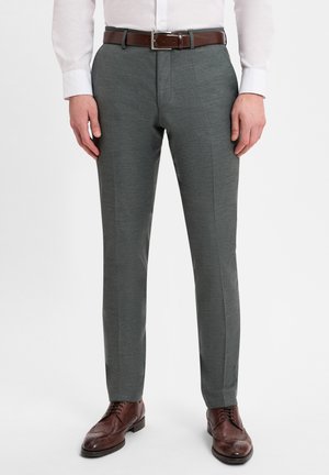Dunkelgraue taillierte Hosen mit einer glatten Textur, die eine schmale Passform, Vorderfalten und einen braunen Ledergürtel aufweisen. Braune Brogueschuhen runden den Look ab.