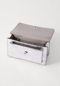 Metalická stříbrná peněženka vyrobená z texturovaného materiálu. Obsahuje patentku, zipovou kapsu a dvě přihrádky na karty nebo hotovost.
