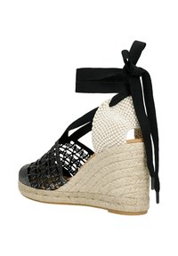 Černobílé wedge sandály s tkaným svrškem, zavazováním kolem kotníku a podpatkem potaženým provazem, které představují stylový letní design obuvi.