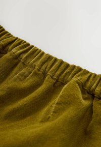 Olive roheline kangas pehme tekstuuriga, mis sisaldab elastset vööd kogutud detailidega. Üksik pind näeb välja pehme ja kutsuv.