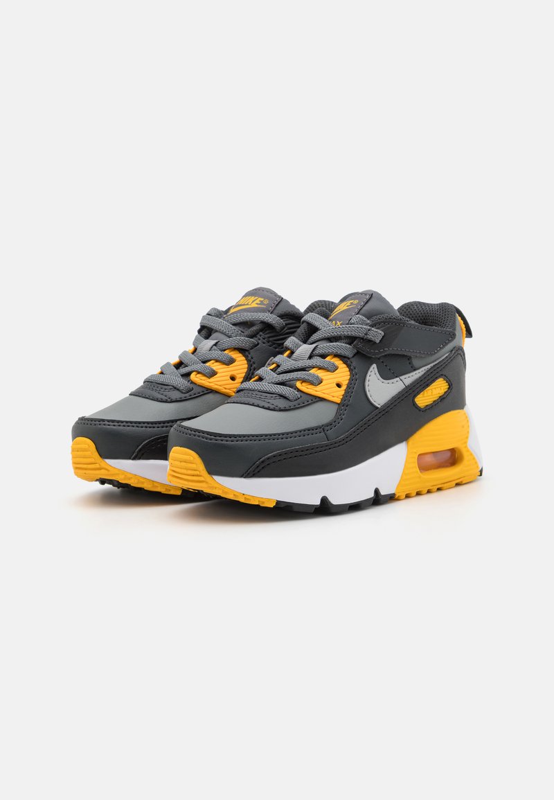 Zapatillas deportivas en gris y amarillo con parte superior de malla y sintético, que cuentan con un collar acolchado, suela de goma y unidad de aire visible.