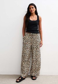 Leopardenmuster weite Hosen mit elastischem Bund, kombiniert mit einem schwarzen gerippten Tanktop und schwarzen Rutschsandalen. Glattes Material, lässiges Design.