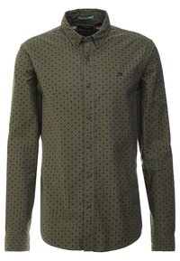 Oliwkowa koszula z guzikami, z subtelnym czarnym wzorem w kropki, długie rękawy i klasyczny kołnierzyk; posiada brązowe guziki.