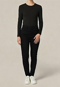 Černý top s dlouhým rukávem a kulatým výstřihem, doplněný vysokými černými džínami a bílými teniskami, vytvářející elegantní siluetu.