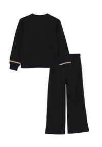 Set di abbigliamento loungewear nero composto da una maglia a maniche lunghe e pantaloni con gamba larga. La maglia presenta dettagli a righe sui polsini, entrambi in tessuto morbido.
