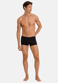 Pánské boxerky v černé barvě vyrobené z jemné látky, mají přiléhavý střih a hladkou texturu, se středním pasem a bez viditelných švů.