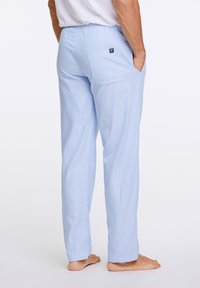 Vaaleansiniset, raidalliset yöpuvun housut, joissa on joustava vyötärö, takatasku ja löysä istuvuus. Kangas vaikuttaa pehmeältä ja kevyeltä.