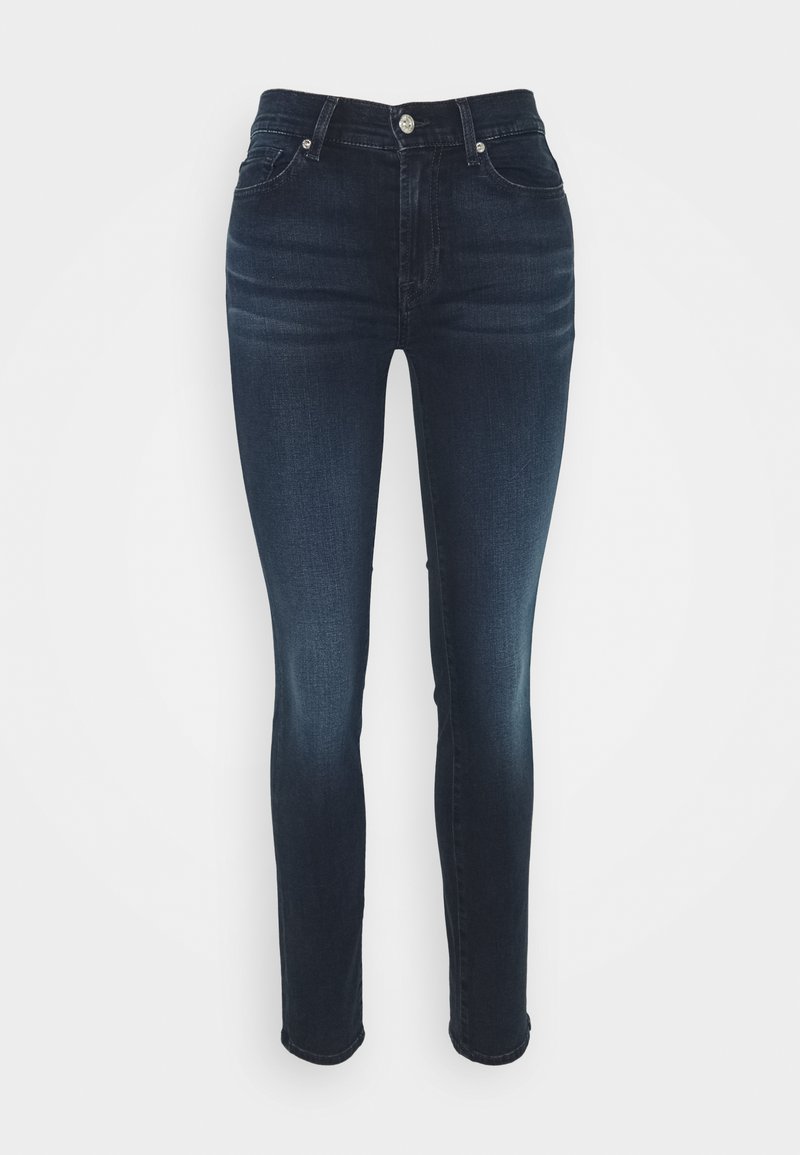 Jeans skinny azul escuro feitos de denim, com cintura alta, cinco bolsos e um desbotado subtil nas pernas. Fecho com botão de metal e zíper.