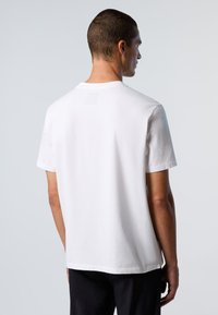 T-shirt bianco in cotone con maniche corte, collo rotondo e un piccolo etichetta sul retro. Tessuto liscio, vestibilità casual e orlo dritto.