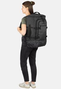 Grauer Stoffrucksack mit schwarzen Akzenten, mehreren Fächern und verstellbaren Trägern, entwickelt für Haltbarkeit und Funktionalität.