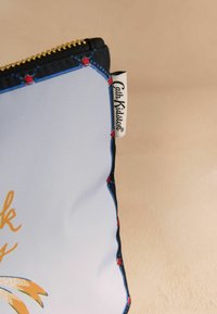 Siniseguga kott, mis on valmistatud pehmest sinisest materjalist punaste tähe aksessuaaridega, musta äärisega ning küljes nähtava логотипmärgiga.