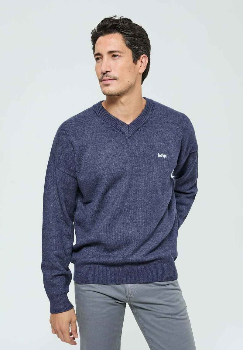 Pull à col en V bleu marine en tissu tricoté texturé, avec un petit logo sur la poitrine gauche et des bords côtelés aux poignets et à l'ourlet.