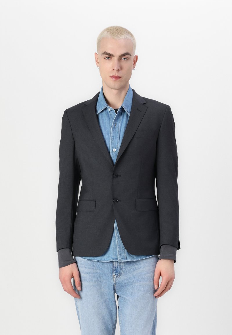 Temno siv eleganten blazer s dvema gumboma, z nazobčanimi reverji in sprednjima žepoma, nosi se čez svetlo modro denim srajco. Gladka tekstura.