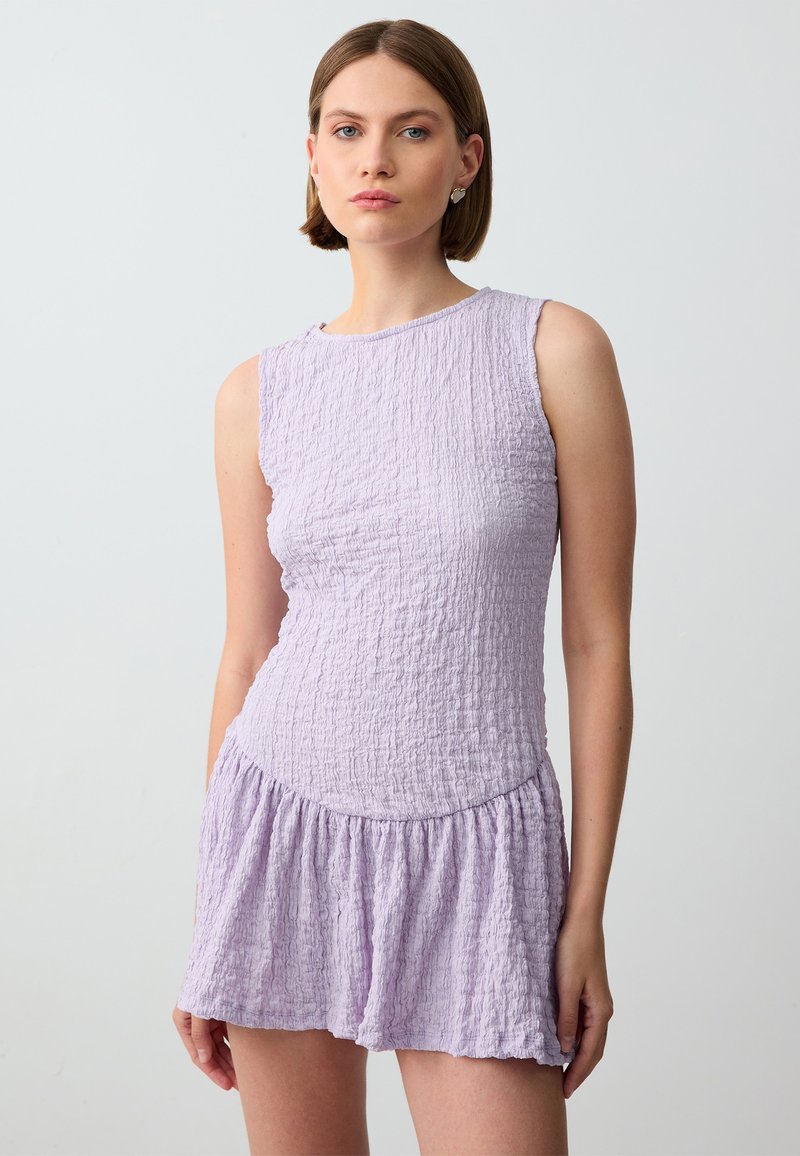Lavendel gekreukt stoffen jurk met een aansluitend lijfje en een uitlopende rok, voorzien van een ronde halslijn en zonder mouwen. Glad textuur.