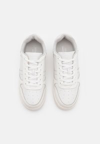 Vita lädersneakers med perforerad tå, runda snören, subtila grå accenter och vadderad krage, med en enkel, strömlinjeformad design.