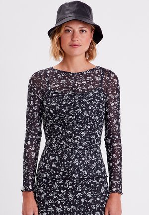 Zwart langemouwen shirt met bloemenprint, voorzien van geraffineerde details en een ronde halslijn, gecombineerd met een zwarte bucket hat.