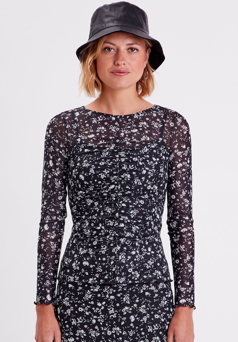 T-shirt noir à manches longues avec imprimé floral, présentant des détails froncés et un col rond, associé à un chapeau seau noir.