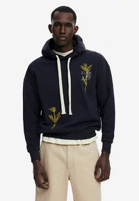 Marineblauwe hoodie van een katoenmix, met gele bloemrijke borduursels op de voorkant, een capuchon met trekkoord en geribde manchetten.