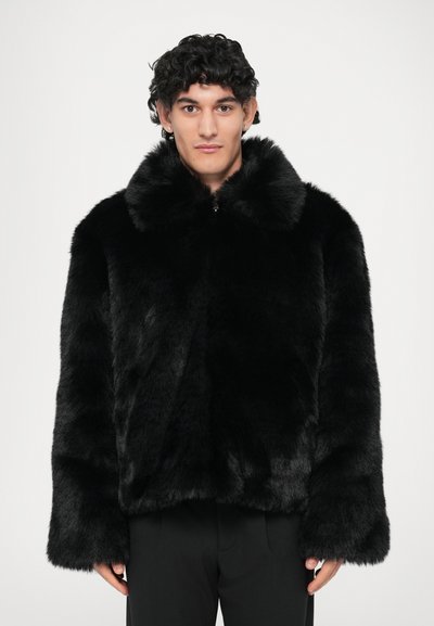 Sort faux fur jakke med bred krave, lange ærmer og en cropped design. Stoffet ser blødt ud med en glat tekstur.
