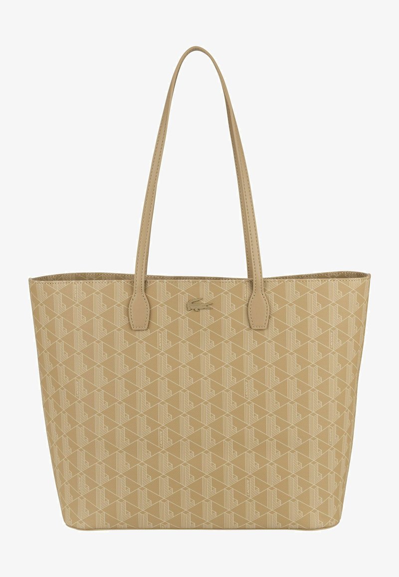Sac fourre-tout beige avec un motif texturé, deux poignées pour les épaules, et un accent logo à l'avant, fabriqué en matériau synthétique. Grand et au design ouvert.