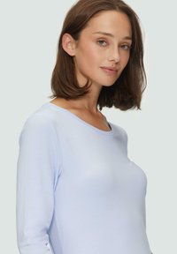 Lichtblauw langemouwen top in zachte stof met een ronde halslijn, aansluitende vorm en een gladde textuur, met minimale designdetails.