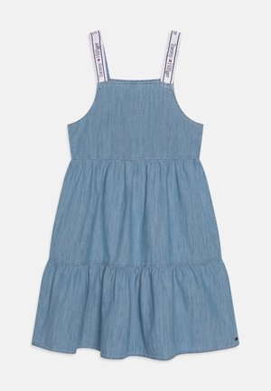 Světle modré denimové šaty s nastavitelnými ramínky, rozšířenou volánkovou sukni a logem na ramínkách. Jednoduchý A-liniový design, každodenní styl.