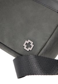 Borsa a tracolla in pelle grigia con superficie texturizzata, dotata di una tracolla intrecciata nera e di un emblematico quadrato argentato sul davanti.