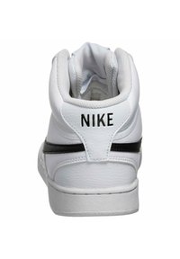 Baskets montantes blanches avec une tige en cuir lisse, détail de bande noire, col rembourré et logo "NIKE" au niveau du talon. Semelle texturée.