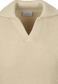 Beige gebreide pullover met een V-hals en ribbelstructuur. Heeft een eenvoudige kraag en een label met de tekst "GESCHIKT" aan de binnenzijde.