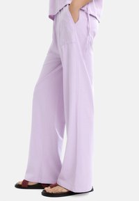 Jasnolawendowe spodnie typu wide-leg wykonane z miękkiego materiału, z dwiema bocznymi kieszeniami i regulowanym paskiem na sznurki.