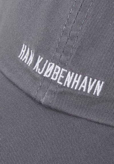 Gray cap made of textured fabric with a curved brim. Features white embroidered text reading "HAN KJØBENHAVN" on the front.