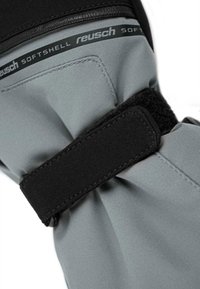 Guante softshell gris con cinta de Velcro negra, que presenta tela fruncida en la muñeca y un delicado detalle de costura. La marca es visible.