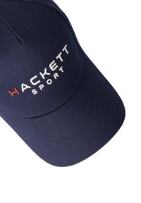 Dunkelblaues Cap mit gebogenem Schirm, aus strukturiertem Stoff. Auf der Vorderseite befindet sich ein weißes "HACKETT"-Logo und "SPORT" in Rot.