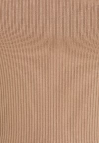Gros plan sur un tissu tricoté côtelé beige avec des rayures verticales texturées et un matériau doux et extensible.