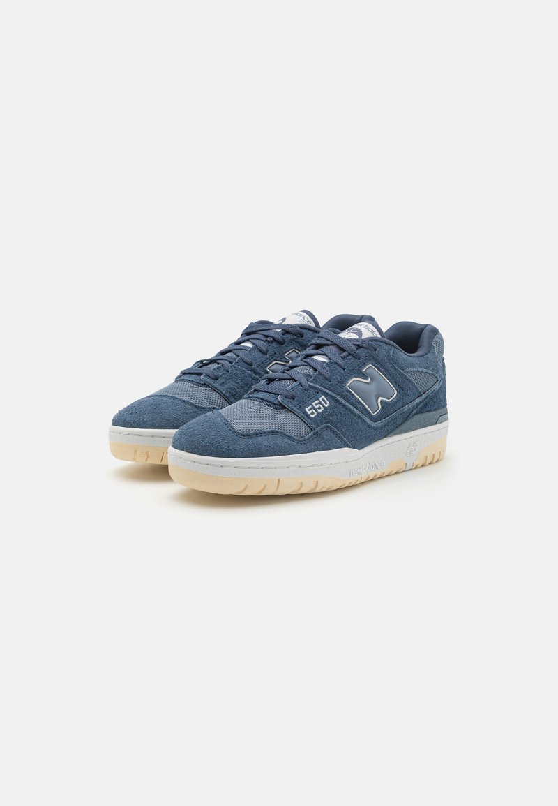 Sneakers blu in suede con pannelli in rete, dettagli bianchi e suole in gomma color crema. Presentano un logo e il numero di modello su un lato.