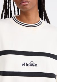 Felpa bianca con righe orizzontali nere, colletto a costine con dettagli in bianco e nero e logo "ellesse" ricamato.