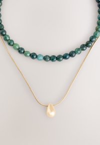 Mehrsträngige Halskette mit dunkelgrünen und blaugrünen facettierten Perlen, mit einer goldenen Kette und einem glänzenden tropfenförmigen Perlenanhänger.