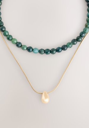 Mehrsträngige Halskette mit dunkelgrünen und blaugrünen facettierten Perlen, mit einer goldenen Kette und einem glänzenden tropfenförmigen Perlenanhänger.